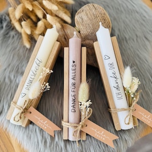 Può includere: Tre portacandele in legno con candele bianche e piccoli mazzi di fiori secchi. Le candele sono etichettate con il testo "Ich danke dir", "Danke für alles" e "Dankelicht".