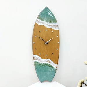 May include: A wooden surfboard clock with a green and blue ocean wave design. The clock face is brown with white accents and silver hands.