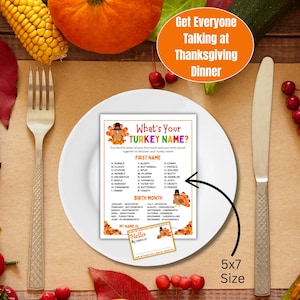 Op de afbeelding: Een Thanksgiving-spelkaart op een wit bord, met een vork en mes. De kaart bevat een kalkoenillustratie en de tekst "What's Your TURKEY NAME?" met een label van 5x7. De achtergrond bevat pompoenen en ma&iuml;s.