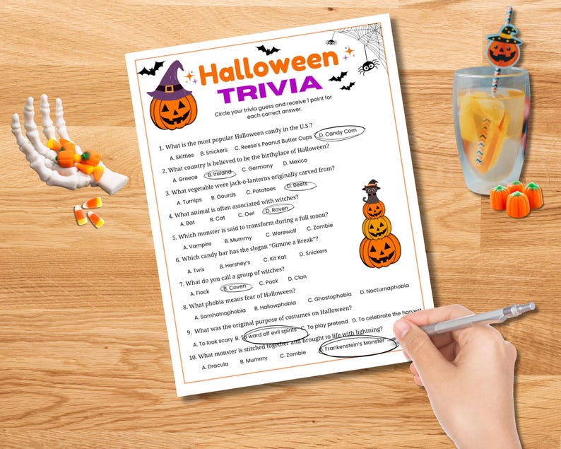 May include: A Halloween trivia game sheet with a pumpkin graphic and the title "Halloween Trivia." The sheet includes multiple-choice questions about Halloween. A hand is circling the correct answers with a pen. Candy corn and a decorative drink are also present.