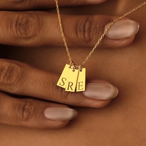 Peut inclure: Un collier en or avec trois petites étiquettes rectangulaires qui épellent "SRE".