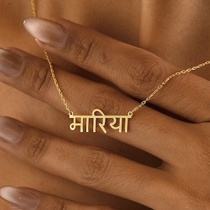 May include: A gold necklace with a pendant that says "मािरया" in Hindi script.