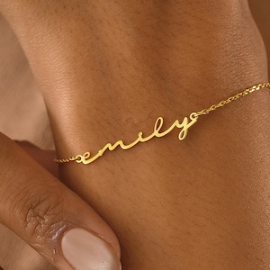 Op de afbeelding: Een gouden kettingarmband met de naam "emily" in cursief.