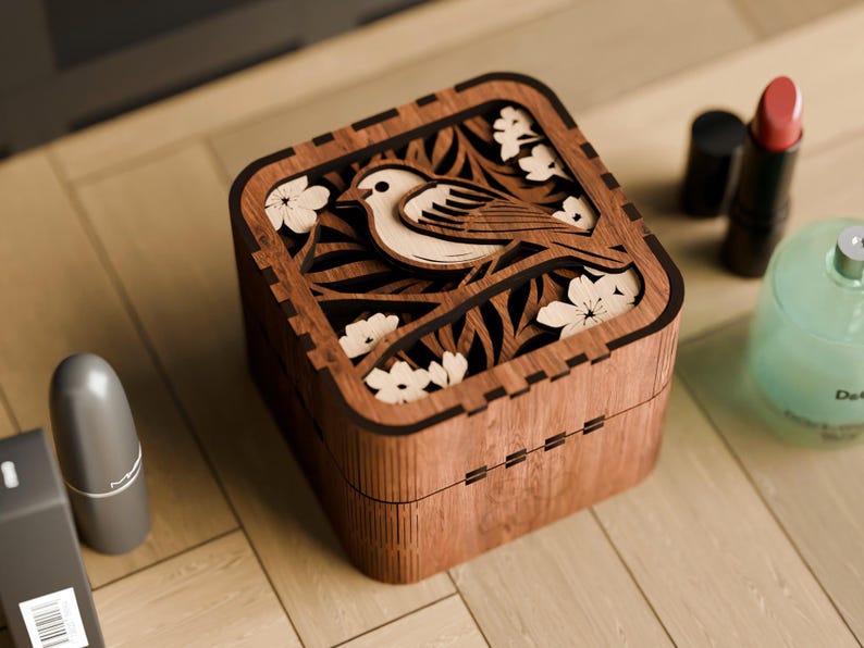 May include: A wooden box with a carved design of a bird and flowers. The box is made of dark wood and has a square shape.