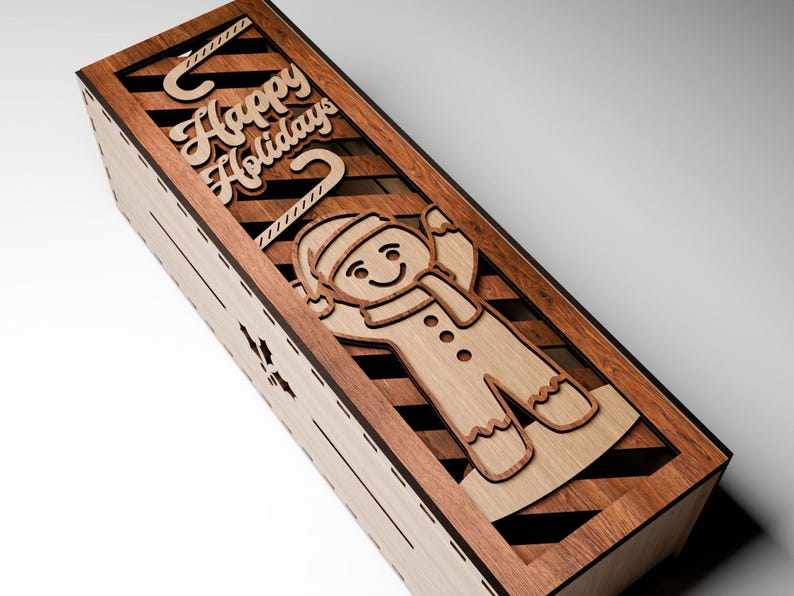 May include: Wooden box with a laser-cut gingerbread man and the words "Happy Holidays." The box is made of light and dark wood, with a diagonal striped pattern. The gingerbread man has a hat and scarf.