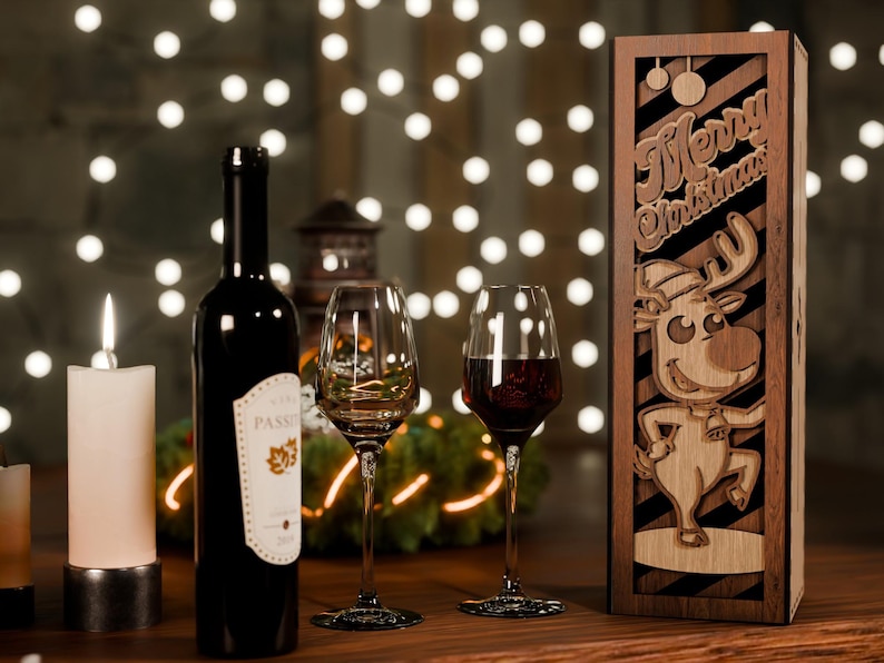 May include: A Christmas-themed wine gift set featuring a dark wine bottle, two wine glasses, and a wooden box with a reindeer design and "Merry Christmas" text. A lit candle and string lights are in the background.