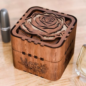 May include: A wooden box with a carved rose design on the lid. The box is brown and has a floral design on the bottom.