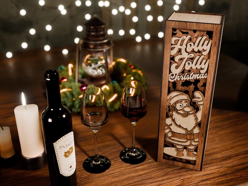 May include: A festive Christmas scene with a wine bottle, two wine glasses, and a wooden box with the words "Holly Jolly Christmas" and a Santa Claus design. A lit candle and fairy lights add to the holiday ambiance.