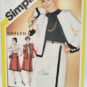 Op de afbeelding: Vintage Simplicity naaipatroon met een vrouw in een witte rok met zwarte bies en bijpassende jas. Het patroon bevat twee maten, 6 & 8. Het merk is Adolfo. De tekst "Simplicity" is prominent aanwezig.
