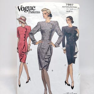 Op de afbeelding: Vogue Patterns naaipatroon envelop met illustraties van drie verschillende jurk ontwerpen. De envelop is wit met het Vogue logo en patroon details. De jurken zijn in tinten rood, grijs en marineblauw, met diverse knoop- en ruchedetails.