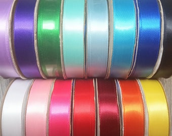 May include: Assortment of 18 spools of satin ribbon in various colors, including white, pink, red, blue, green, and yellow. The ribbon is wound around cardboard spools.