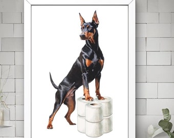 Puede incluir: Obra de arte enmarcada que presenta un Doberman Pinscher negro y canela de pie sobre una pila de rollos de papel higiénico blancos. El perro es el punto focal, sobre un fondo blanco. La obra se exhibe en un baño moderno.