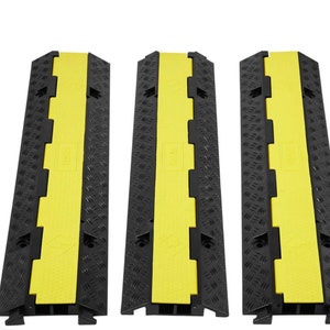 Może przedstawiać: Trzy czarne i żółte osłony kabli. Każda osłona ma żółty kanał środkowy i czarną powierzchnię w romby. Krawędzie są również czarne z zazębiającymi się zębami. Widoczna jest nazwa marki.