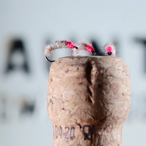 May include: Two pink and white fly fishing lures with a hook on a cork.