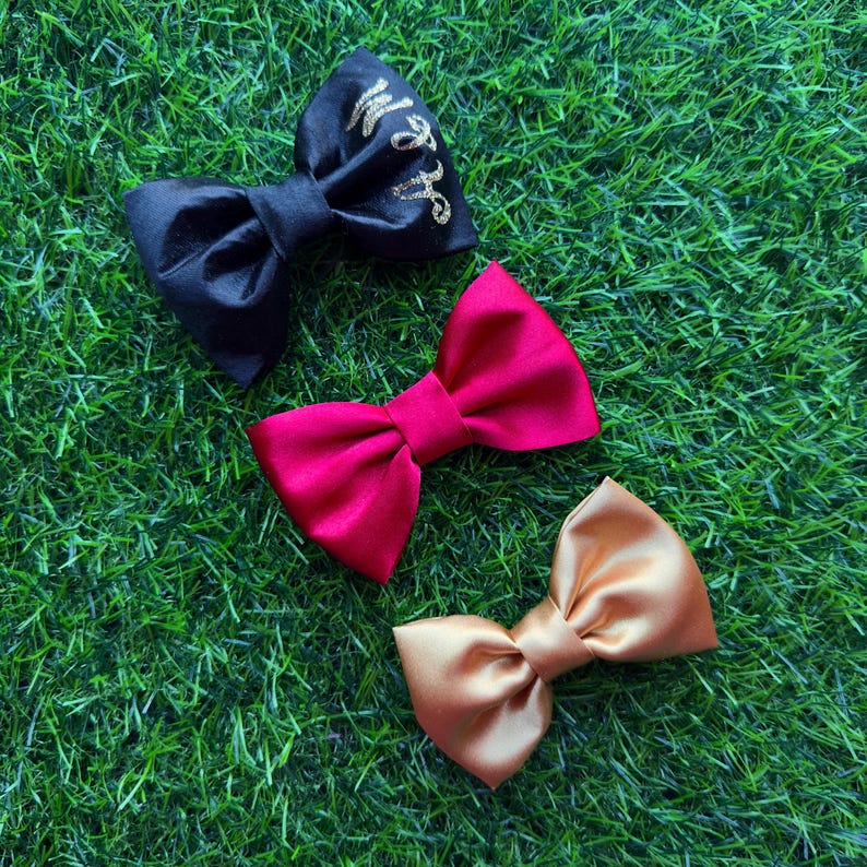 May include: Three satin bow hair clips in black, red, and gold. The black bow has gold glitter lettering that says "Wife".