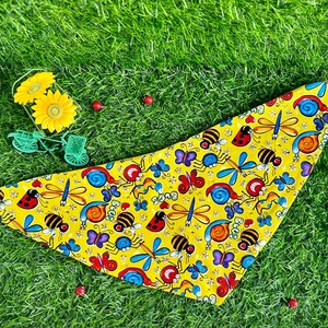 Op de afbeelding: Gele bandana met een herhaald patroon van cartoon insecten, waaronder bijen, lieveheersbeestjes, vlinders en libellen. Het woord "Bugs" staat ook op de bandana. De bandana is driehoekig.