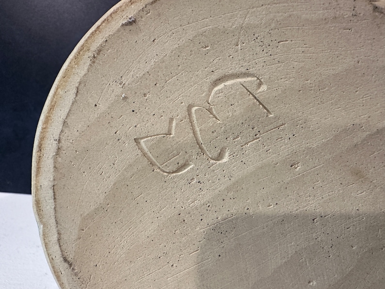 Op de afbeelding: Close-up van de onderkant van een keramische vaas met de letters "EC" gestempeld in de bodem.