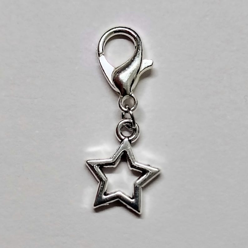 May include: Silver star charm with a lobster clasp. The star has an open center.