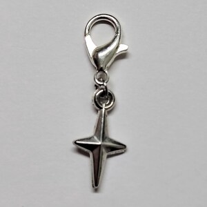 May include: Silver charm with a star-shaped pendant and a lobster clasp.