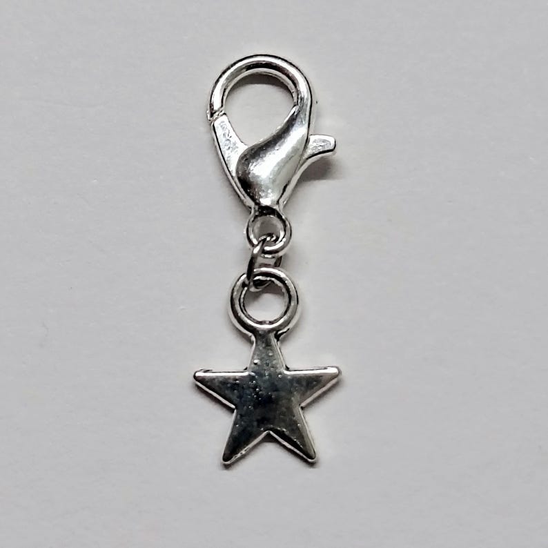 May include: Silver star charm with a lobster clasp. The star is attached to a small silver ring.