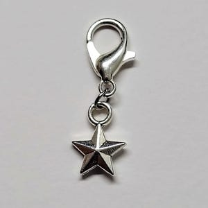 May include: Silver star charm with a silver lobster clasp. The charm is about 1 inch in diameter.