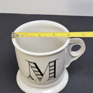 May include: A set of three ceramic mugs with a speckled, matte finish. The mugs are in shades of cream, light gray, and dark gray. Each mug has a simple, minimalist design and a rounded handle.