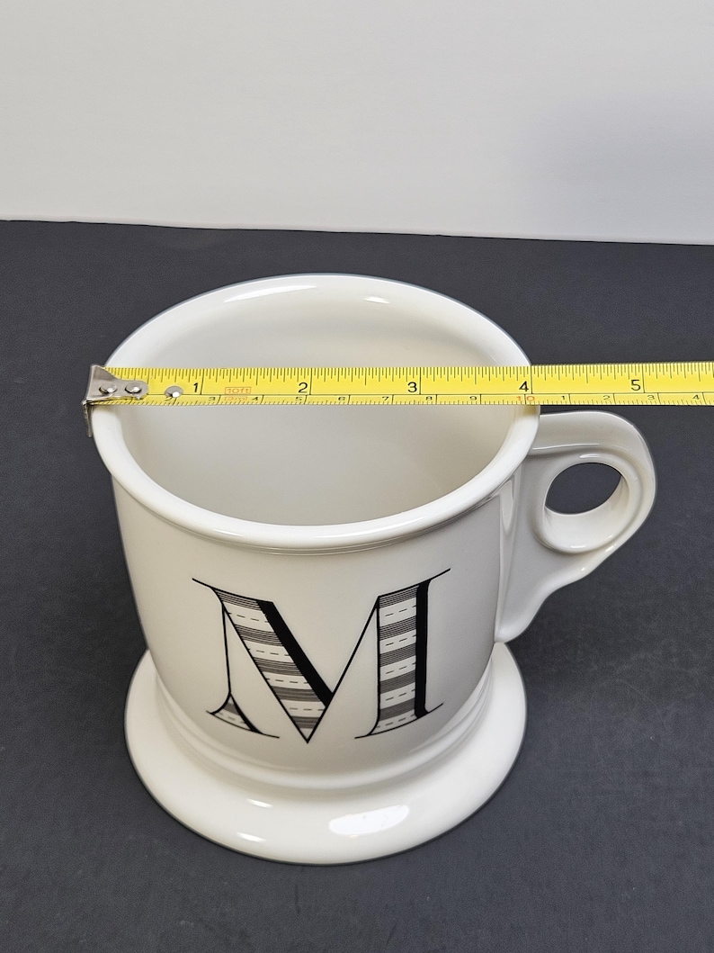 May include: A set of three ceramic mugs with a speckled, matte finish. The mugs are in shades of cream, light gray, and dark gray. Each mug has a simple, minimalist design and a rounded handle.