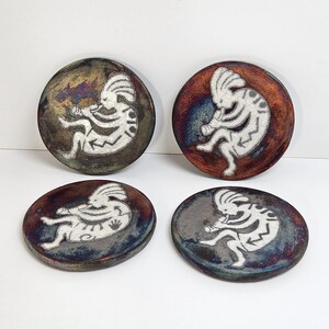 May include: A white ceramic mug with a black handle and the text "But First, Coffee" in a black, bold font. The mug is sitting on a wooden surface. The mug is approximately 4 inches tall.