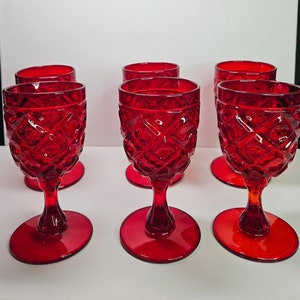 May include: Set of six red glass goblets with a diamond pattern. The goblets have a clear base and a wide bowl.