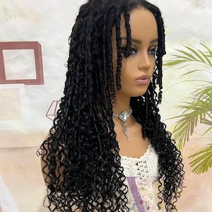 Puede incluir: Una peluca larga y negra con el pelo suelto, rizado y con textura. La peluca está peinada con raya lateral y el pelo está recogido de la cara en un lado.