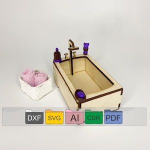 May include: A wooden miniature bathtub with a purple faucet, soap bottle, and towel. The bathtub is sitting on a white surface with a white wicker basket filled with a pink towel.