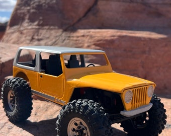 May include: A yellow and white toy jeep with large black tires, sitting on a rocky surface. The jeep has a white roof and a black interior. The jeep is a scale model of a real jeep.