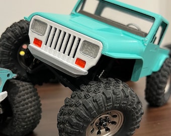 Op de afbeelding: Een turquoise blauwe speelgoedtruck met een witte grille en zwarte banden. De truck is opgetild op blokken en heeft een zwarte en zilveren velg.