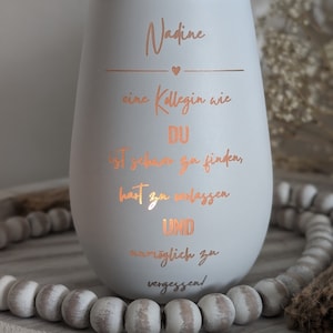 May include: A white ceramic candle holder with a rose gold inscription that reads "Nadine, a colleague like you is hard to find, hard to replace and impossible to forget!"