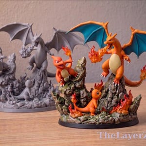 May include: A painted figurine set featuring Charizard, Charmeleon, and Charmander on a rocky base with flames, alongside an unpainted gray resin version of the same scene. The text TheLayerZero is visible in the bottom right corner.