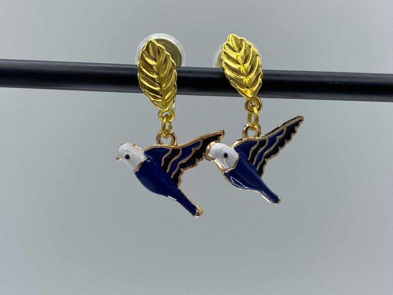 Clip on earrings with blue and gold flying birds, dangling from golden leaves