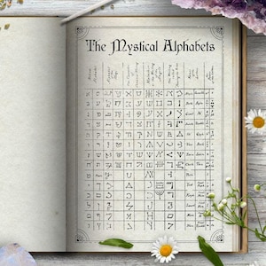 Puede incluir: Un libro abierto con un fondo blanco y una página llena de una tabla de los alfabetos místicos. El libro está rodeado de hierbas secas, flores y cristales sobre una superficie de madera blanca.