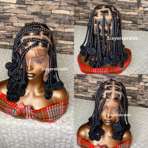 May include: A black braided wig with a lace front and a bun design. The wig is on a mannequin head with a red and black plaid scarf. The text "Slayersbraids" is visible on the image.
