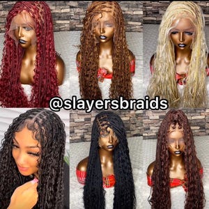 May include: Six different braided wigs with curly ends. The wigs are in various colors, including red, brown, blonde, and black. The wigs are on mannequin heads and are styled in a long, flowing style. The image includes the text "@slayersbraids".