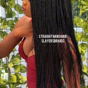 May include: Long, straight black nano hair braids. The image features the text "STRAIGHT NANO HAIR SLAYERSBRAIDS". The braids are styled to fall down the back. The background includes green and yellow leafy plants.