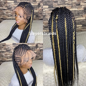 May include: A black and gold braided wig with a lace front. The wig features a combination of black and gold braids, with a side part and a natural-looking hairline. The text "Slayersbraids" is visible.