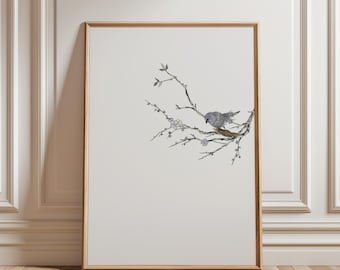 May include: Framed art print featuring a detailed illustration of a small gray bird perched on a branch with delicate leaves and small white flowers. The artwork is set against a neutral background, framed in a light wood.