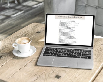 May include: A silver laptop computer with a white screen displaying a list of 101 content ideas for equestrians. The laptop is on a wooden table with a cup of coffee.