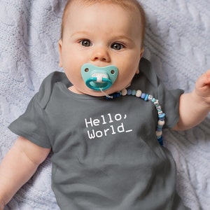 May include: A baby wearing a gray onesie with the text "Hello, World_" in white. The baby is wearing a blue and white pacifier and a blue and white beaded necklace.