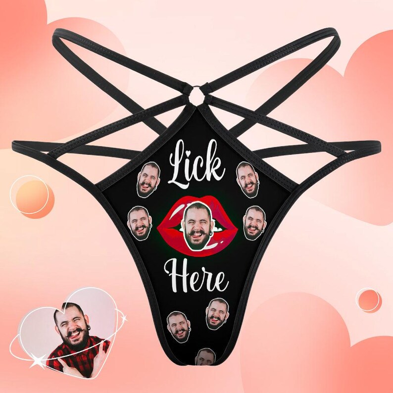 Puede incluir: Braga tanga negra con un dise&ntilde;o &uacute;nico. El panel frontal presenta el texto "Lick Here" sobre un gr&aacute;fico de labios rojos con una cara en el centro. M&uacute;ltiples caras rodean el gr&aacute;fico de labios. Las correas son negras.