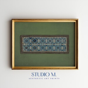 Puede incluir: Una lámina rectangular en un marco dorado con fondo verde y una banda horizontal central con un patrón geométrico de estrellas azules y blancas, rodeada por un borde griego negro. El texto STUDIO M. AESTHETIC ART PRINTS aparece en la parte inferior.