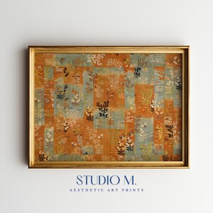Può includere: Una stampa artistica rettangolare in una cornice dorata con un motivo a strisce verticali di pannelli alternati in arancione bruciato e blu tenue. Il design mostra un motivo botanico ripetuto di piccoli fiori, foglie e steli in bianco e nero.