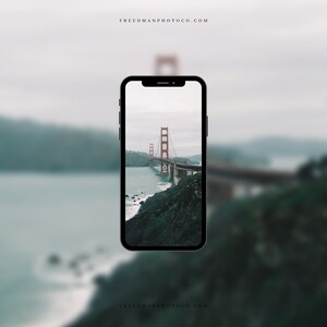 May include: A black smartphone displaying a photo of the Golden Gate Bridge in San Francisco, California. The bridge is red and spans a body of water. The photo is taken from a distance, showing the bridge in its entirety.