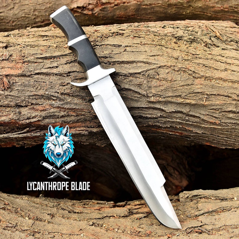May include: A silver and black knife with a black handle and a wolf logo with the text "LYCANTHROPE BLADE". The knife is resting on a piece of wood.