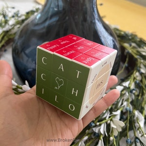 May include: A green and white cube puzzle with the word "CATCH" on one side and the words "Fill the Hearts of Your Faithful" on another side. The cube also has the words "Holy Spirit" and "IHS" on other sides.
